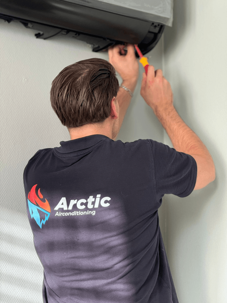 Monteur repareert airconditioning aan muur.